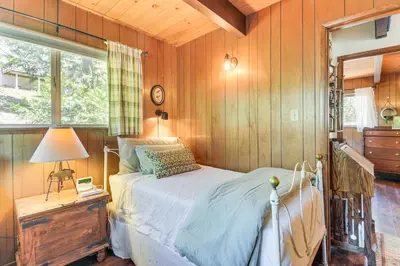 a bedroom with a bed and a lamp and a window at The Green Hideaway Arnold Cabin in the Pines! in Arnold