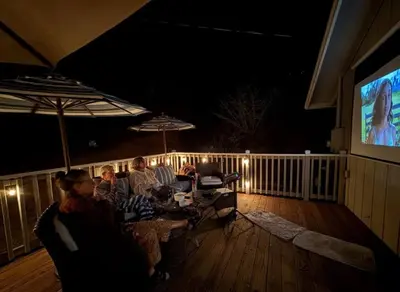a group of people sitting on a deck watching tv at StayCation Sierra – Nonpareil Retreat in Groveland