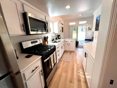 a kitchen with white cabinets and a stove top oven at Bright Modern Tiny Retreat with Yoga Dome Near Yosemite, Groveland, California in Groveland