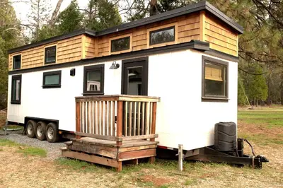 a tiny house on a trailer in a field at Cozy Modern Tiny Retreat with Yoga Dome, Garden, and Stargazing in Groveland, California in Groveland