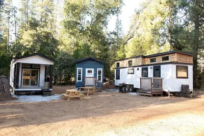 a couple of tiny homes parked in the woods at Cozy Modern Tiny Retreat with Yoga Dome, Garden, and Stargazing in Groveland, California in Groveland