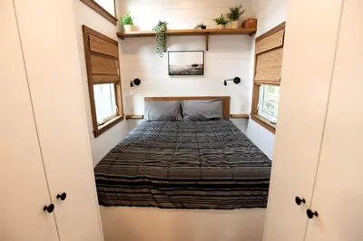 a bed in a tiny house with two windows at Cozy Modern Tiny Retreat with Yoga Dome, Garden, and Stargazing in Groveland, California in Groveland