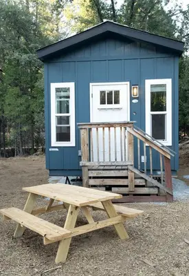 a picnic table and a bench in front of a blue shack at Charming Bright Tiny Home with Stargazing & Yoga Dome Near Yosemite, Groveland, California in Groveland