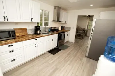 a kitchen with white cabinets and a stainless steel refrigerator at Cozy Nature-Filled Home with Garden & Night Sky Views Near Yosemite Tioga Pass, Groveland CA in Groveland