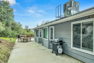 a house with a patio and a grill on the side at Twilight Villa,Hot Tub,EV Charger,Yosemite and Bass lake in Oakhurst