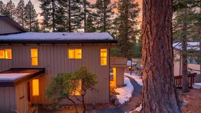 a tiny house with lights on in the woods at Pinecone Peak by AvantStay Incline Village Condo Fireplace Balconies Pool Access in Incline Village