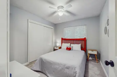 a bedroom with a red bed and a ceiling fan at Whispering Pines Retreat in South Lake Tahoe