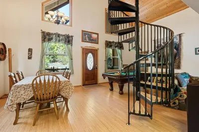 a living room with a spiral staircase and a table at Mountain Paradise- Family Cabin w Pool Table in Shaver Lake