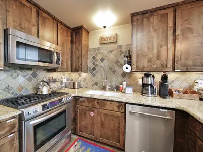 a kitchen with wooden cabinets and stainless steel appliances at Kirkwood Mountainside Cabin Views Walk to Lifts in Kirkwood