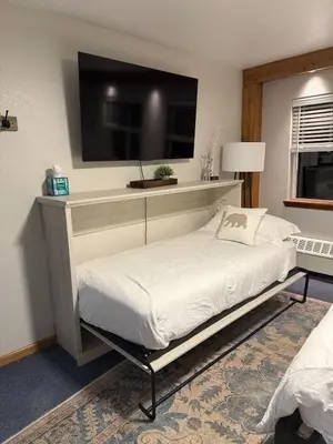 a bedroom with a bed with a tv on the wall at The Meadows- Charmed Hotel Unit Steps to Ski Lifts in Kirkwood