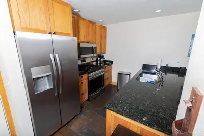 a kitchen with a stainless steel refrigerator and wooden cabinets at The Meadows - 2 Bdrm Family Condo in Kirkwood in Kirkwood