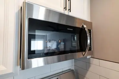 a microwave oven in a kitchen with white cabinets at Walk to the lifts hot tub covered parking luxury in Kirkwood
