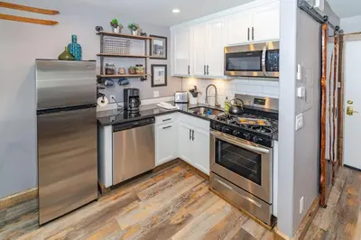 a kitchen with stainless steel appliances and wooden floors at Walk to the lifts hot tub covered parking luxury in Kirkwood