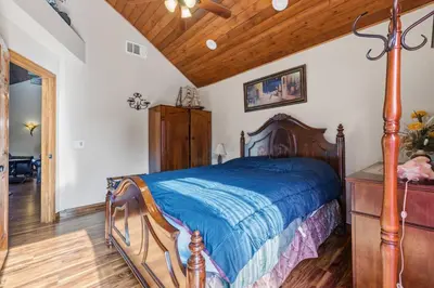 a bedroom with a wooden bed with a blue comforter at Gorgeous cottage in fair oaks village in Fair Oaks