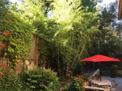 a patio with a table and a red umbrella at Charming vintage village house in Fair Oaks
