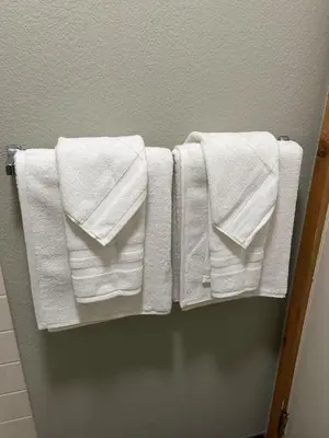 three white towels are hanging on a rack in a bathroom at The Meadows- Modern 1BedroomDeck and Fireplace in Kirkwood