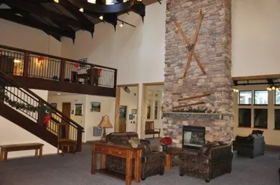 a living room with a stone fireplace with a large clock at The Meadows Modern Suite Deck & Garage Parking in Kirkwood