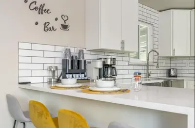 a white kitchen with yellow chairs and a counter top at Pet-Friendly Home - Big Yard for Family Stays in Sacramento