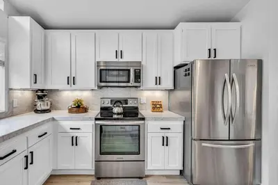 a kitchen with white cabinets and a stainless steel refrigerator at Tahoe Retreat - Private Hot Tub & Scenic Views in Incline Village
