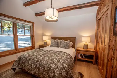 a bedroom with a bed and two lamps and a window at Cedar Cottage in Homewood