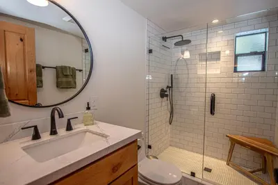 a bathroom with a sink and a shower with a mirror at Cedar Cottage in Homewood