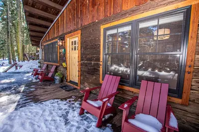 a group of chairs sitting outside of a cabin in the snow at Cedar Cottage in Homewood