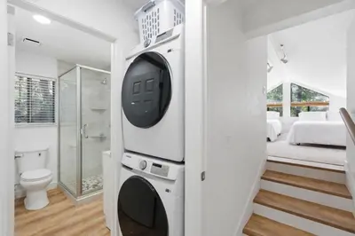 a bathroom with a washer and dryer next to a bedroom at Shaver Escape Hot Tub Cabin Retreat with AC in Shaver Lake