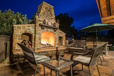 a patio with a stone fireplace with a table and chairs at Nature's Inn Bed and Breakfast in Ahwahnee