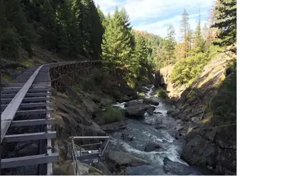a bridge over a river next to a river at The Cozy Knotty Pine Enchantment Retreat in Long Barn