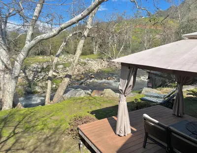 a wooden deck with a gazebo next to a river at Cozy Riverfront Home with EV charger in Three Rivers