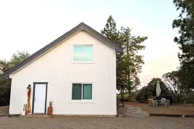 a white house with a window and a door at Cozy Woodworker's Cabin, 26 miles to Yosemite! in Midpines