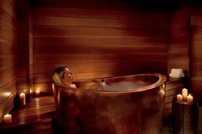 a woman sitting in a copper tub in a room with candles at Northstar Ritz-Carlton in Truckee