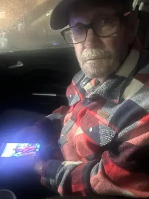 a man sitting in a car with a cell phone at Rancho Grand Mobile Home Park in Atwater