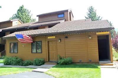 a house with an american flag in front of it at Mountain Condo | Spa Pool and Ski Shuttle Access in Mammoth Lakes