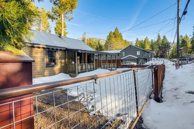 a house with a fence in the snow at Close to Lake and Heavenly Mtn Resort! Quaint Cabin in South Lake Tahoe