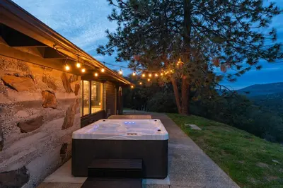 a patio with a table and lights on a building at New! Stunning views Hot tub King beds in Oakhurst