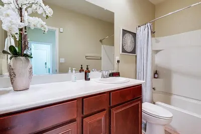 a bathroom with a sink and a toilet and a vase of flowers at Sophisticated Sanctuary 8 Mi to Lodi Wineries! in Stockton