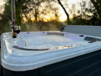 a hot tub with a glass of wine and a glass of red wine at Vista Chalet near Yosemite and Bass Lake in Oakhurst