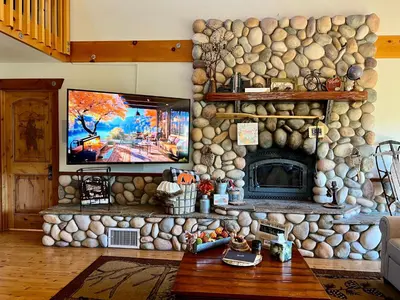 a living room with a stone fireplace and a tv at Vista Chalet near Yosemite and Bass Lake in Oakhurst