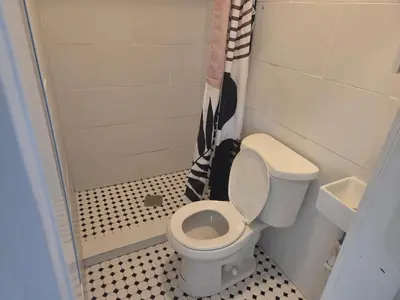 a small bathroom with a toilet and a shower at La Lomas Bohemian Courtyard Cottage in Modesto