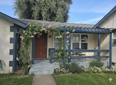 a house with a pergola with pink roses on it at La Lomas Bohemian Courtyard Cottage in Modesto