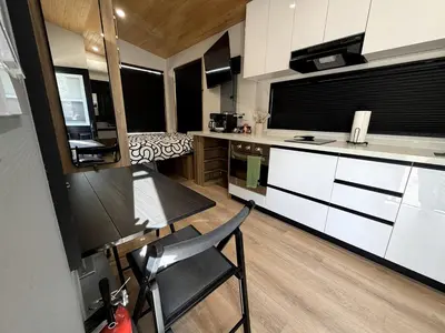 a kitchen with white cabinets and a table and chairs at Stylish Modern Tiny House on Wheels with Stunning Mountain Views Near Lone Pine, California in Lone Pine
