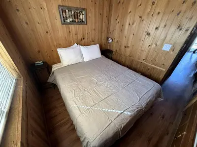 a small bedroom with a bed in a wooden wall at Cozy Mountain-Style Cabin with Scenic Sierra Nevada Views Near Lone Pine, California in Lone Pine