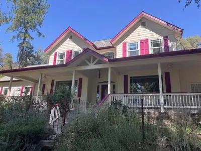 a pink and white house with a porch at The Firehouse Inn-Cottage in Mariposa