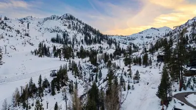 a snow covered mountain with trees and a ski lift at The Traverse by AvantStay Ski-InSki-Out Condo • Pool Hot Tub Access • Steps to KT-22 in Olympic Valley
