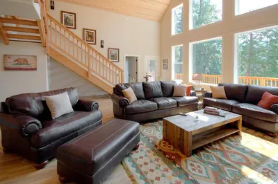 a living room with leather furniture and a staircase at River Rock Retreat in Yosemite West