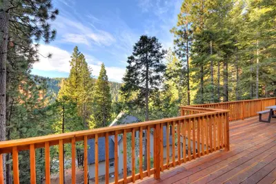 a wooden deck with a bench and a view of the forest at River Rock Retreat in Yosemite West