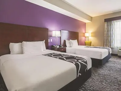 two beds in a hotel room with purple walls at La Quinta by Wyndham Fresno Northwest in Fresno
