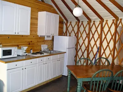 a kitchen with a white refrigerator and a table at Yosemite Lakes Hillside Yurt 14 in Harden Flat