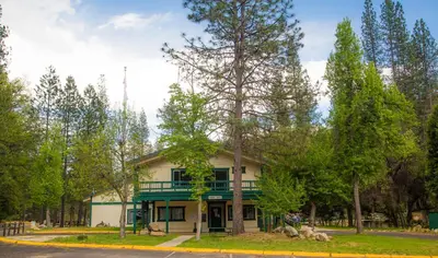 a house with a green porch and trees at Yosemite Lakes Wheelchair Accessible Meadow Yurt 16 in Harden Flat